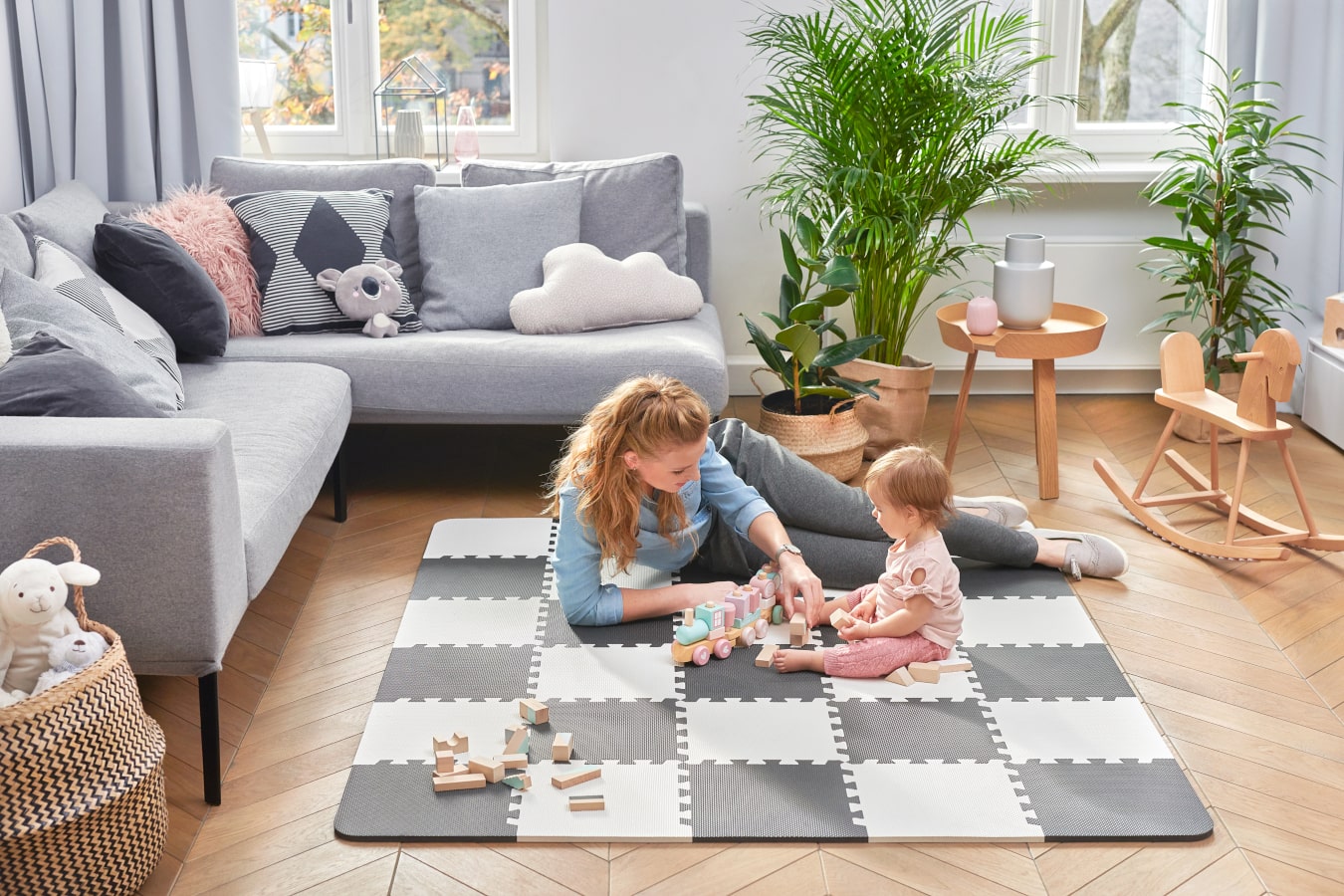 In salotto, la mamma e la bambina giocano insieme sul tappetino educativo LUNO.