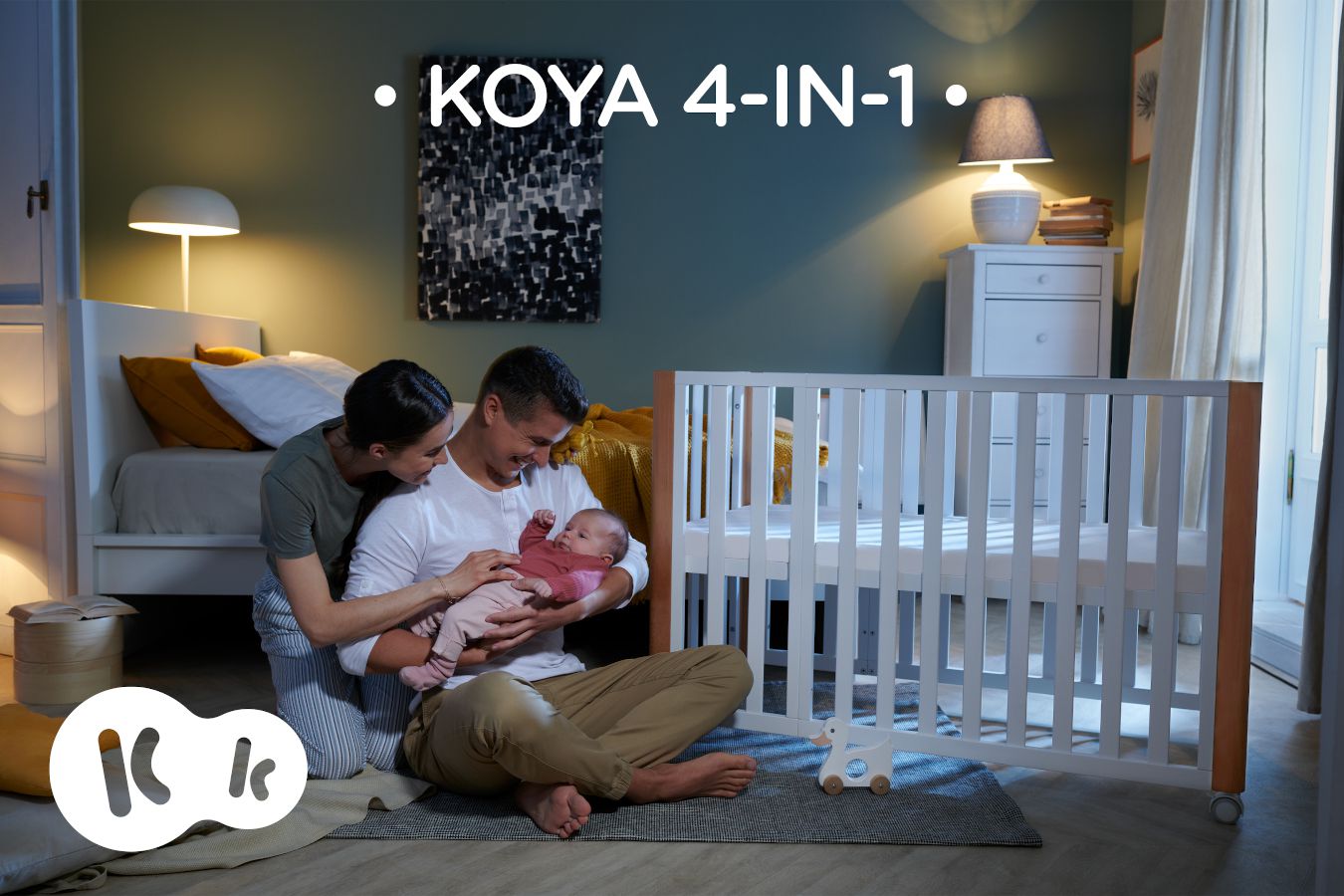 A casa, i genitori con il bambino sono seduti accanto alla culla KOYA con l'iscrizione KOYA 4IN1.